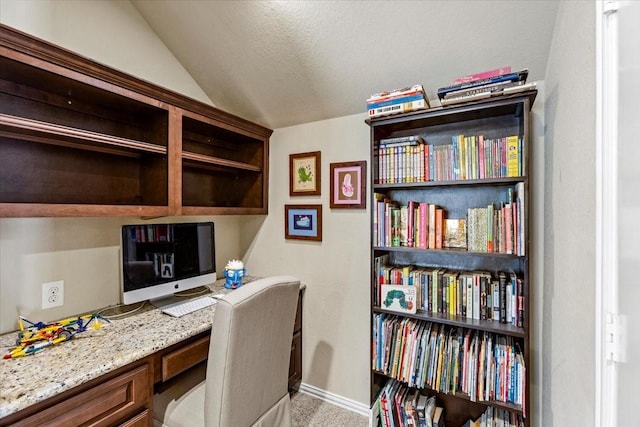 carpeted office featuring built in desk and vaulted ceiling