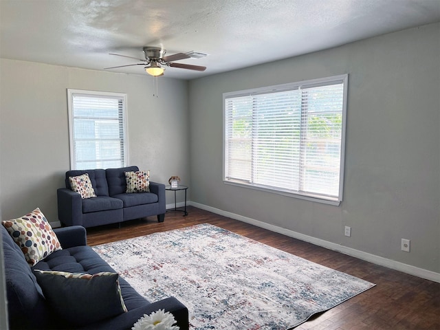 living room featuring ceiling fan and dark wood-type flooring