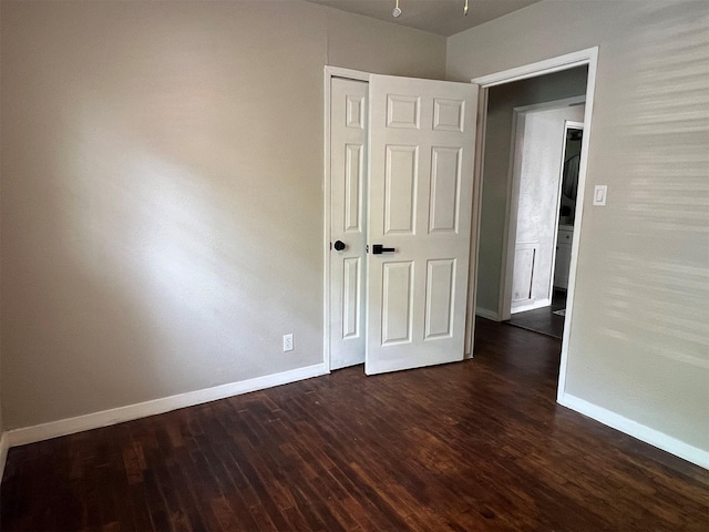 unfurnished bedroom with dark hardwood / wood-style flooring and a closet