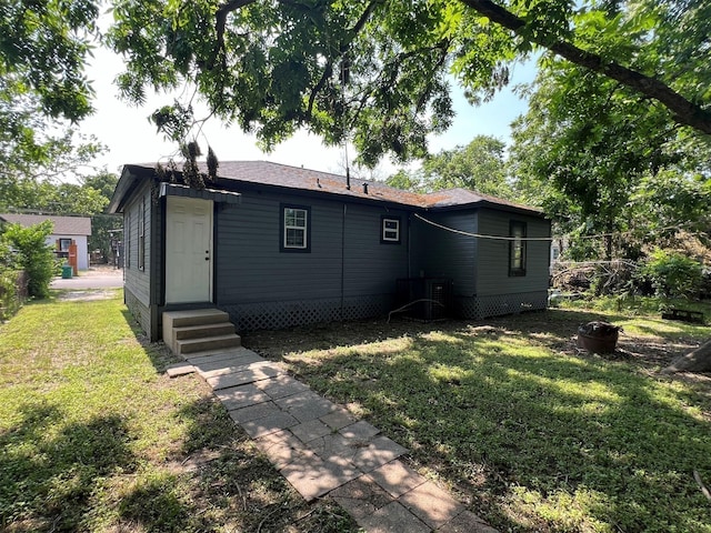 back of house with central AC unit and a yard