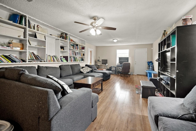 living room featuring ceiling fan, light hardwood / wood-style floors, and a textured ceiling