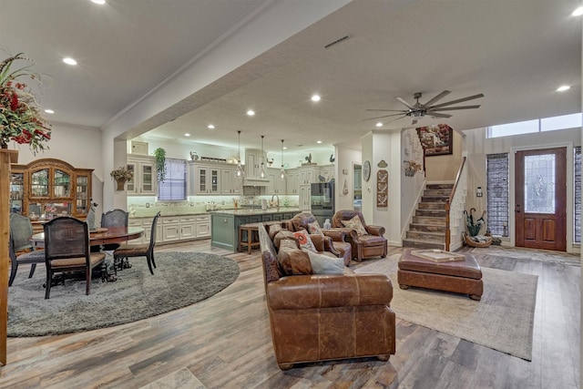 living room with ceiling fan, light wood-type flooring, and crown molding