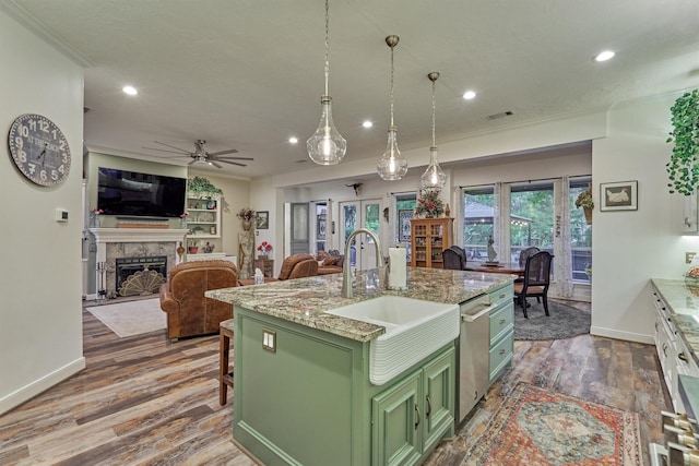 kitchen featuring a center island with sink, green cabinets, sink, light stone counters, and dark hardwood / wood-style flooring