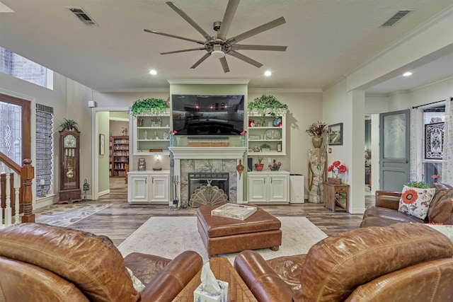 living room with a tiled fireplace, ceiling fan, hardwood / wood-style floors, and crown molding