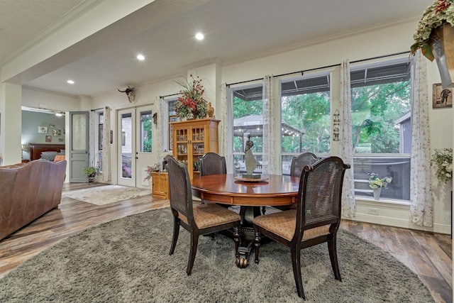 dining area featuring plenty of natural light, wood-type flooring, ornamental molding, and french doors