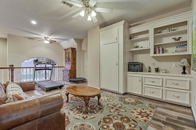 living room featuring ceiling fan, dark hardwood / wood-style flooring, and a textured ceiling