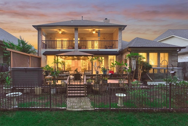 back house at dusk with ceiling fan, a balcony, and a patio