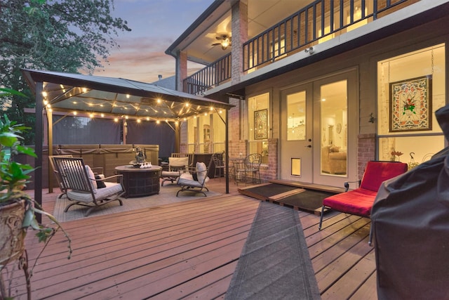 deck at dusk featuring a gazebo and a hot tub