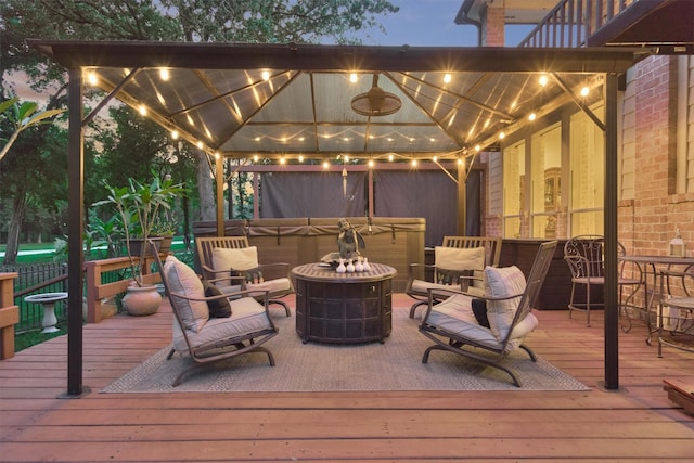 deck at dusk with a gazebo, a hot tub, and a fire pit