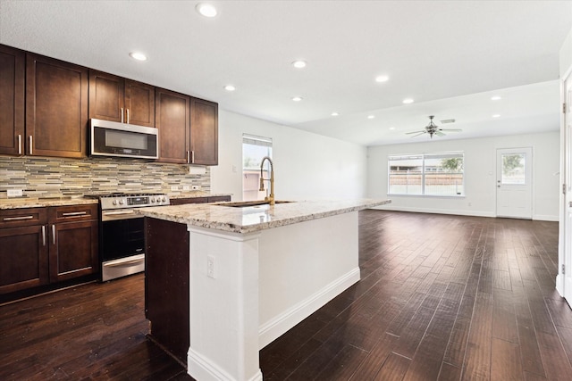 kitchen featuring ceiling fan, sink, a kitchen island with sink, decorative backsplash, and appliances with stainless steel finishes