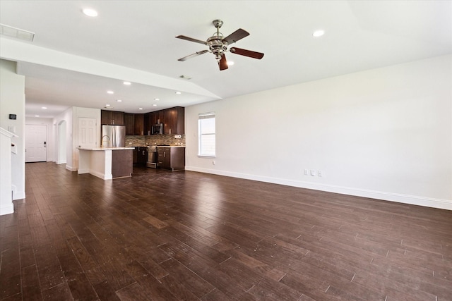 unfurnished living room featuring dark hardwood / wood-style floors, vaulted ceiling, and ceiling fan