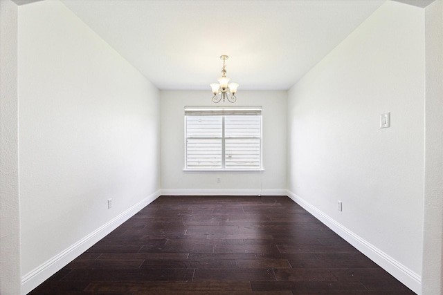 spare room featuring dark hardwood / wood-style floors and a notable chandelier