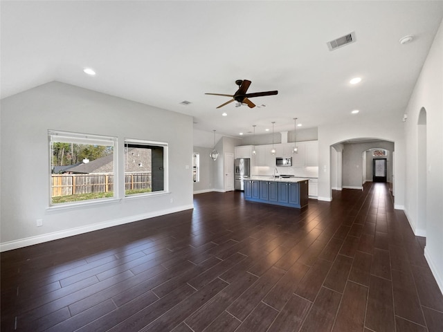 unfurnished living room featuring ceiling fan with notable chandelier and sink