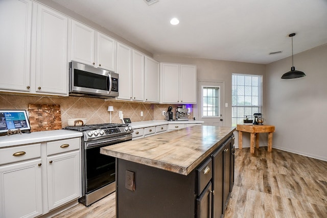 kitchen featuring hanging light fixtures, decorative backsplash, a kitchen island, white cabinetry, and stainless steel appliances