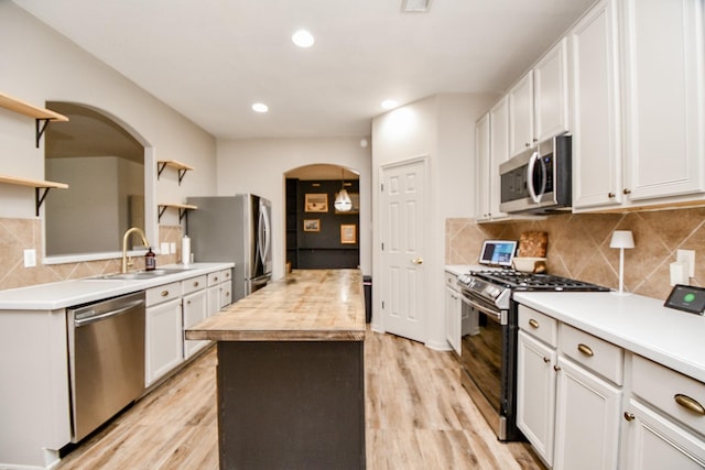 kitchen featuring sink, decorative backsplash, appliances with stainless steel finishes, light hardwood / wood-style floors, and white cabinetry