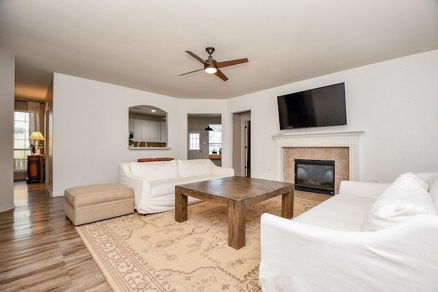 living room featuring hardwood / wood-style flooring, plenty of natural light, ceiling fan, and a tiled fireplace