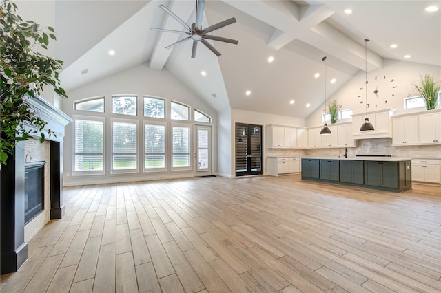 unfurnished living room with ceiling fan, light hardwood / wood-style floors, and high vaulted ceiling