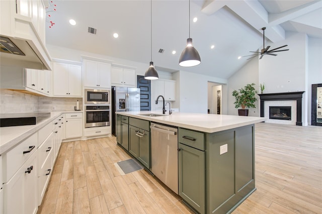 kitchen with a kitchen island with sink, green cabinets, sink, white cabinetry, and stainless steel appliances