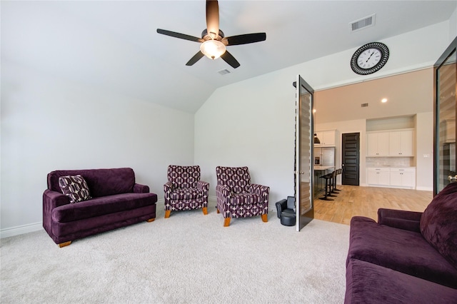 living room featuring ceiling fan, light carpet, and vaulted ceiling