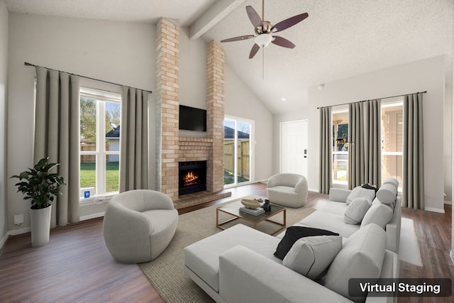 living room with lofted ceiling with beams, ceiling fan, a textured ceiling, a fireplace, and wood-type flooring