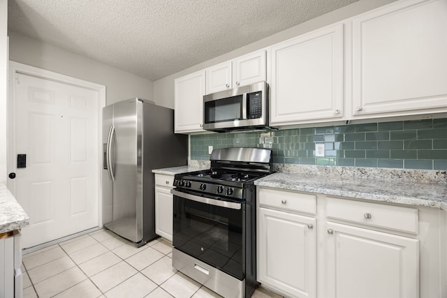 kitchen featuring tasteful backsplash, light stone counters, a textured ceiling, stainless steel appliances, and white cabinets