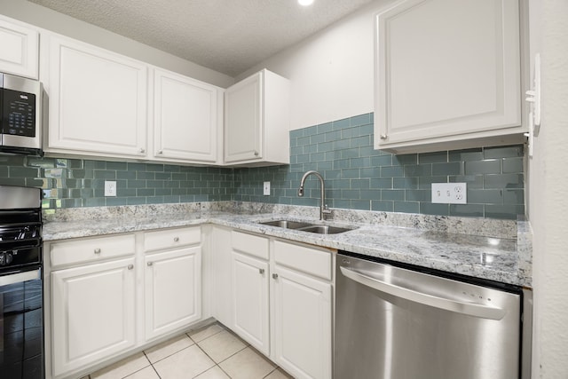 kitchen with white cabinetry, sink, light tile patterned floors, and stainless steel appliances