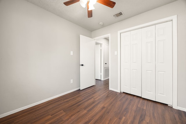 unfurnished bedroom featuring ceiling fan, a closet, dark wood-type flooring, and a textured ceiling