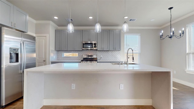 kitchen featuring gray cabinetry, stainless steel appliances, sink, hanging light fixtures, and an island with sink