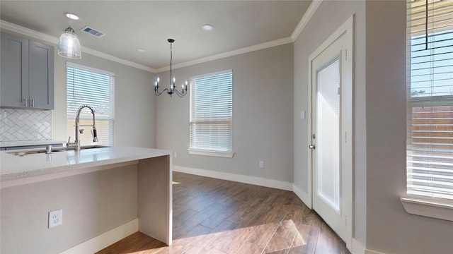 kitchen featuring backsplash, gray cabinetry, ornamental molding, sink, and a notable chandelier