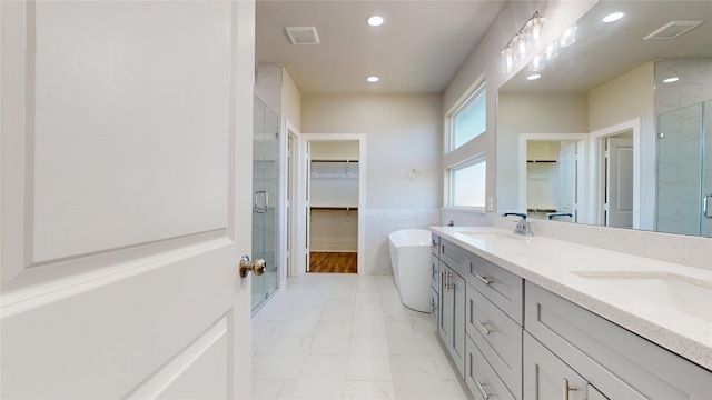 bathroom featuring vanity, independent shower and bath, and tile walls