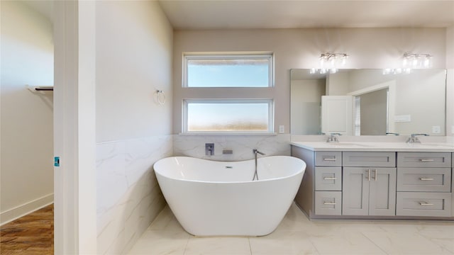 bathroom with vanity, tile walls, and a tub