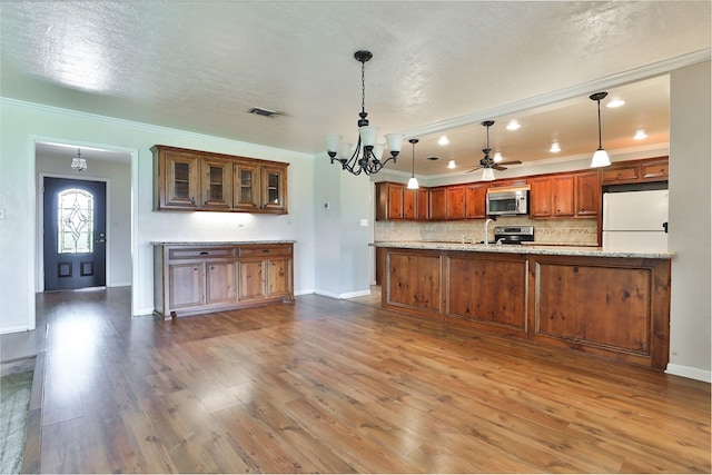 kitchen featuring backsplash, crown molding, appliances with stainless steel finishes, decorative light fixtures, and kitchen peninsula