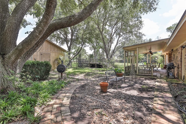 view of yard featuring ceiling fan and a deck