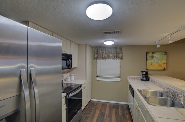 kitchen with sink, rail lighting, stainless steel appliances, a textured ceiling, and white cabinets