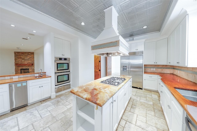 kitchen featuring a center island, white cabinets, sink, appliances with stainless steel finishes, and custom range hood