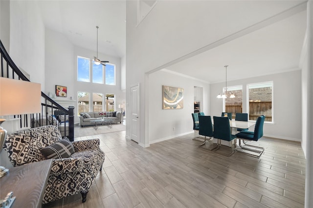 living room with a high ceiling, ceiling fan with notable chandelier, and ornamental molding