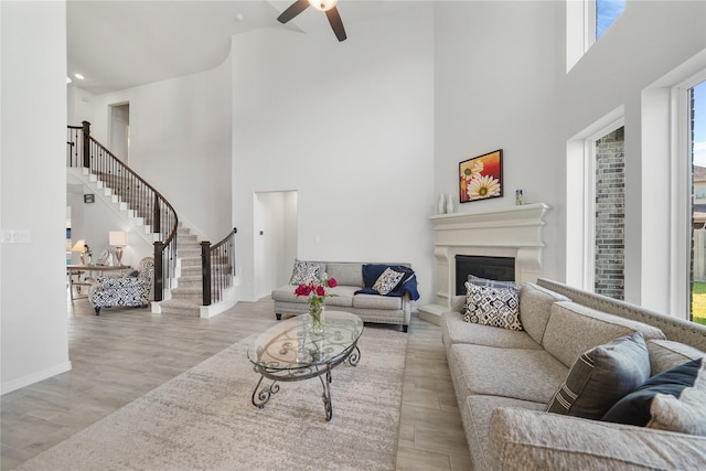 living room featuring a high ceiling, light hardwood / wood-style floors, and ceiling fan