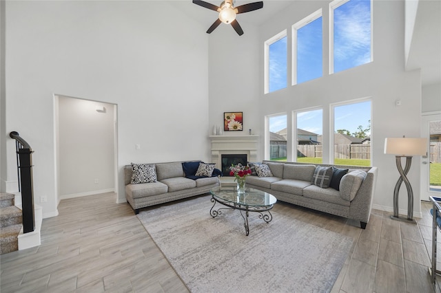 living room featuring ceiling fan, plenty of natural light, and a towering ceiling