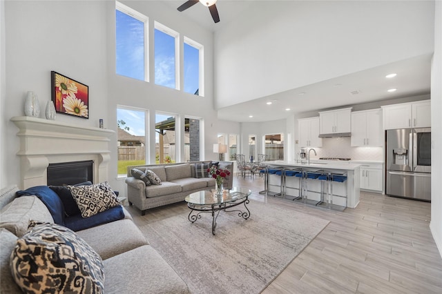 living room featuring a high ceiling, ceiling fan, and sink