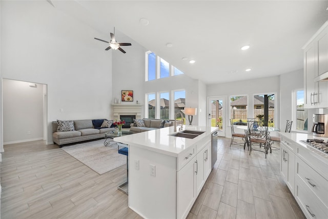 kitchen featuring a center island with sink, sink, ceiling fan, white cabinetry, and a breakfast bar area