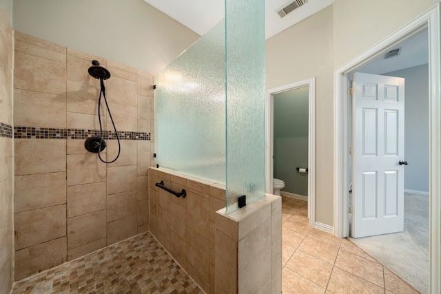 bathroom featuring tile patterned floors, toilet, and tiled shower