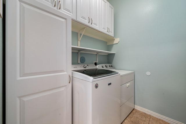 clothes washing area featuring washer and dryer, cabinets, and light tile patterned floors