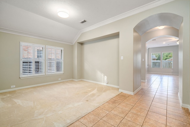 spare room featuring vaulted ceiling, ornamental molding, and light tile patterned flooring