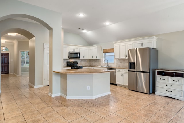 kitchen featuring sink, vaulted ceiling, decorative backsplash, white cabinetry, and stainless steel appliances