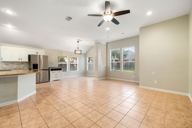 unfurnished living room with light tile patterned floors, ceiling fan with notable chandelier, vaulted ceiling, and plenty of natural light