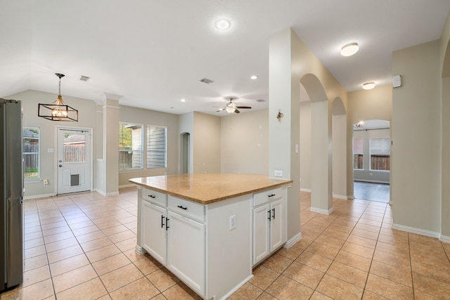 kitchen with white cabinetry, a center island, stainless steel fridge, decorative light fixtures, and ceiling fan with notable chandelier