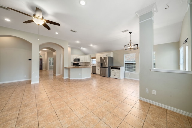 kitchen with stainless steel appliances, pendant lighting, lofted ceiling, white cabinets, and ceiling fan with notable chandelier