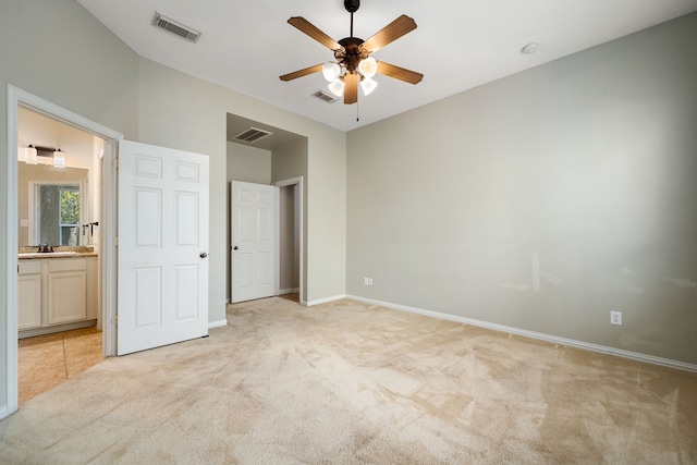 unfurnished bedroom with ensuite bath, ceiling fan, sink, and light carpet