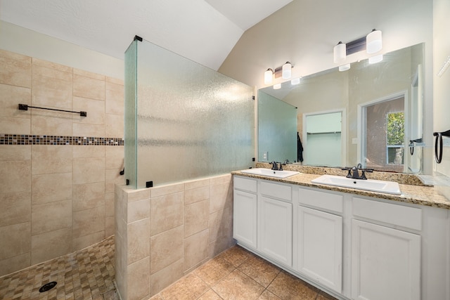 bathroom featuring a tile shower, tile patterned floors, vanity, and lofted ceiling