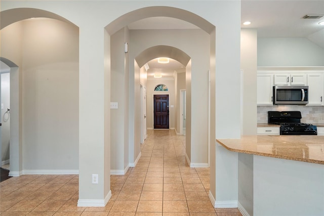 hall featuring light tile patterned floors and crown molding